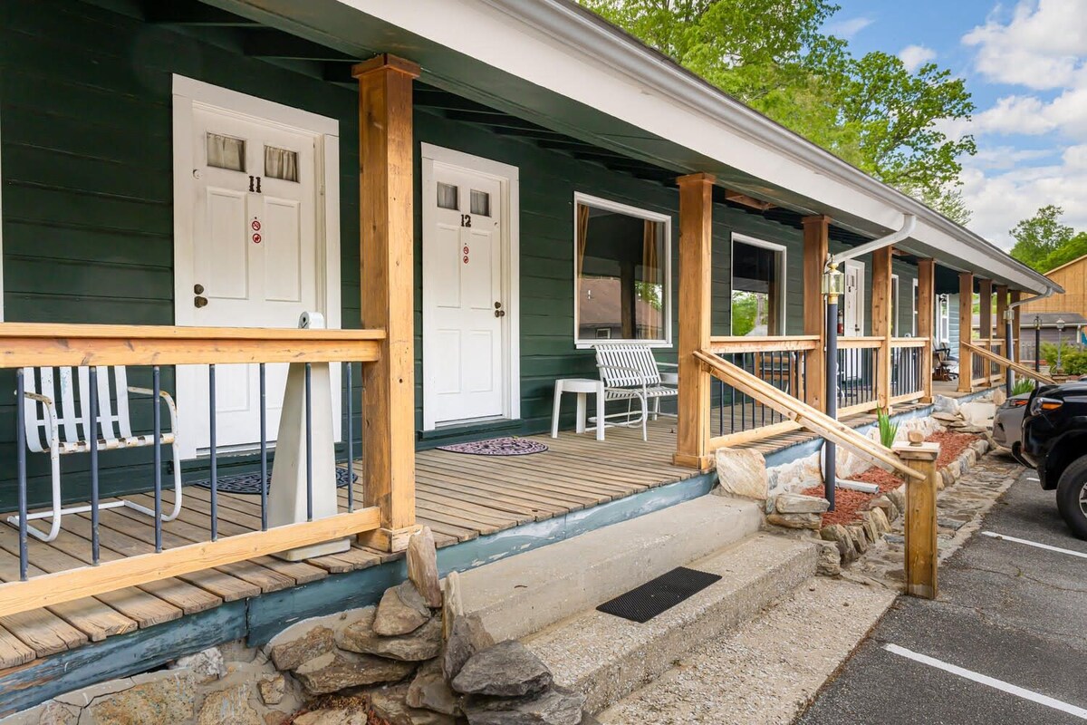 A wooden porch with a stone pathway leading to a set of white doors, each marked with a number.