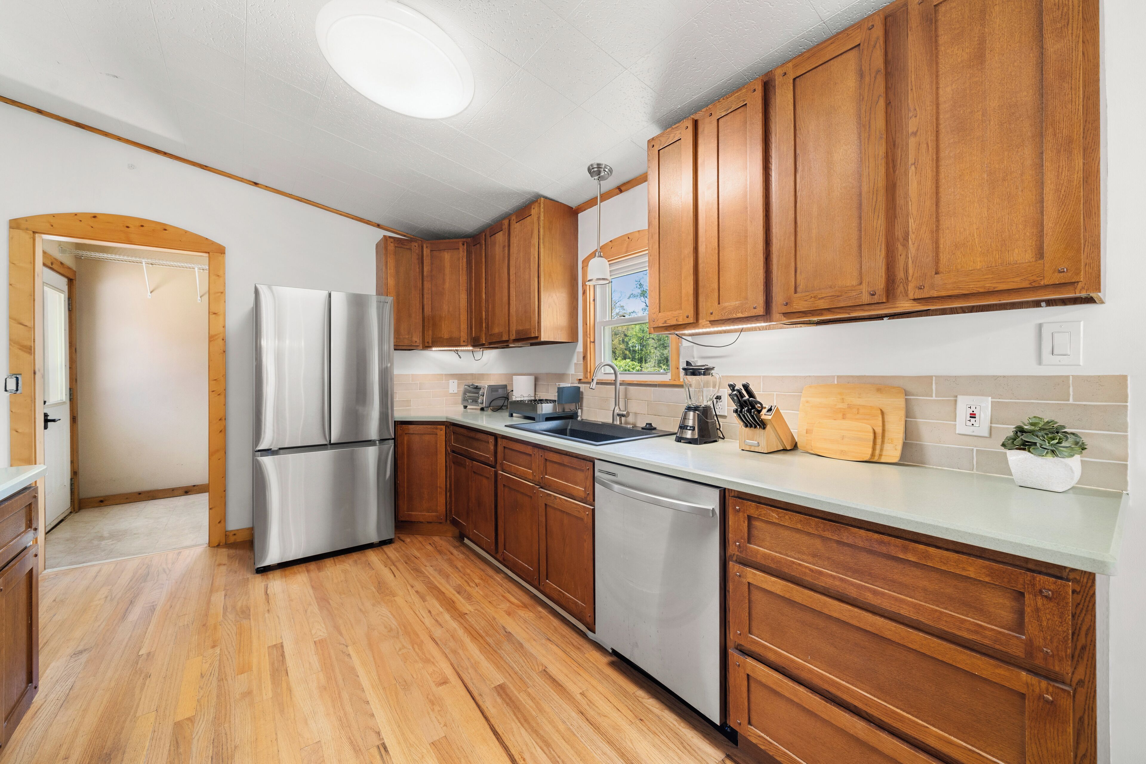 A modern kitchen with wooden cabinets, stainless steel appliances, and a light-colored countertop.