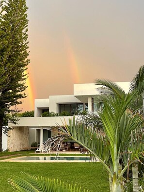 Ein modernes Haus mit Pool und üppiger Bepflanzung.