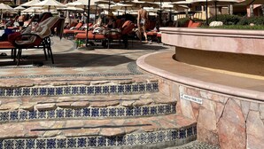 A resort pool area with sun loungers, umbrellas, and a tiled staircase leading to a pool. - 5 minutes walking distance to Cabo Marina yet private w/security (Cabo San Lucas)