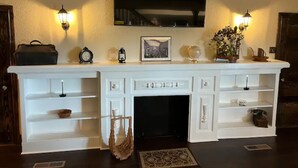 A white console table with a flat-screen TV above, flanked by wall sconces. - 1920s Farmhouse  (Wichita Falls)