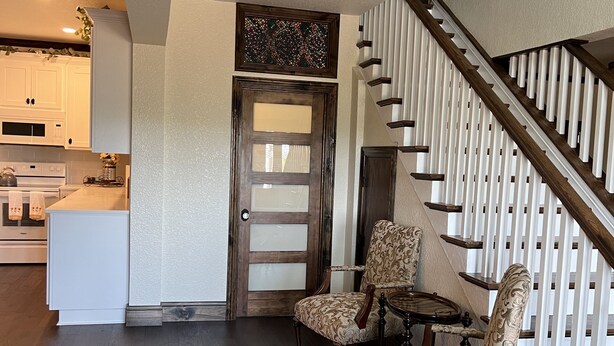 A spacious living area with a staircase, wooden flooring, and a dining table with chairs. - 1920s Farmhouse  (Wichita Falls)