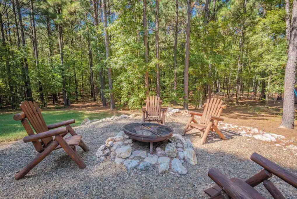 Un espace boisé avec un foyer et deux fauteuils Adirondack.