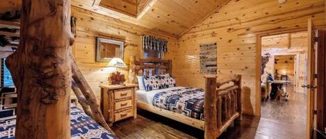 A log cabin bedroom with a bed, nightstands, and a wooden tree trunk.