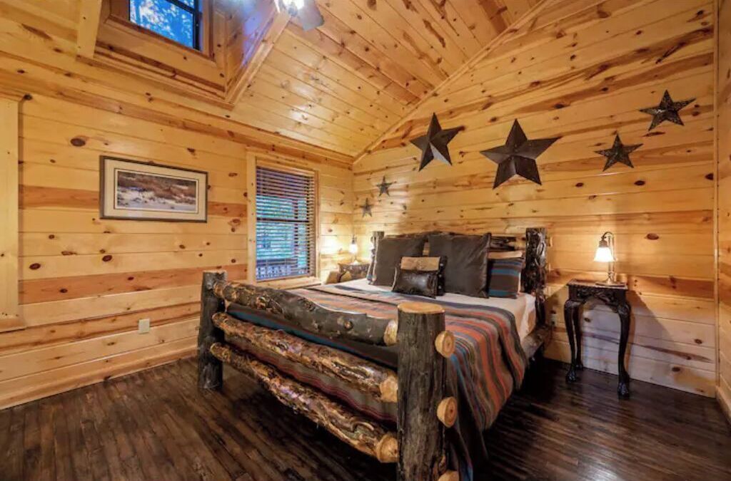 A log cabin bedroom with a rustic bed, wooden walls, and star decorations.