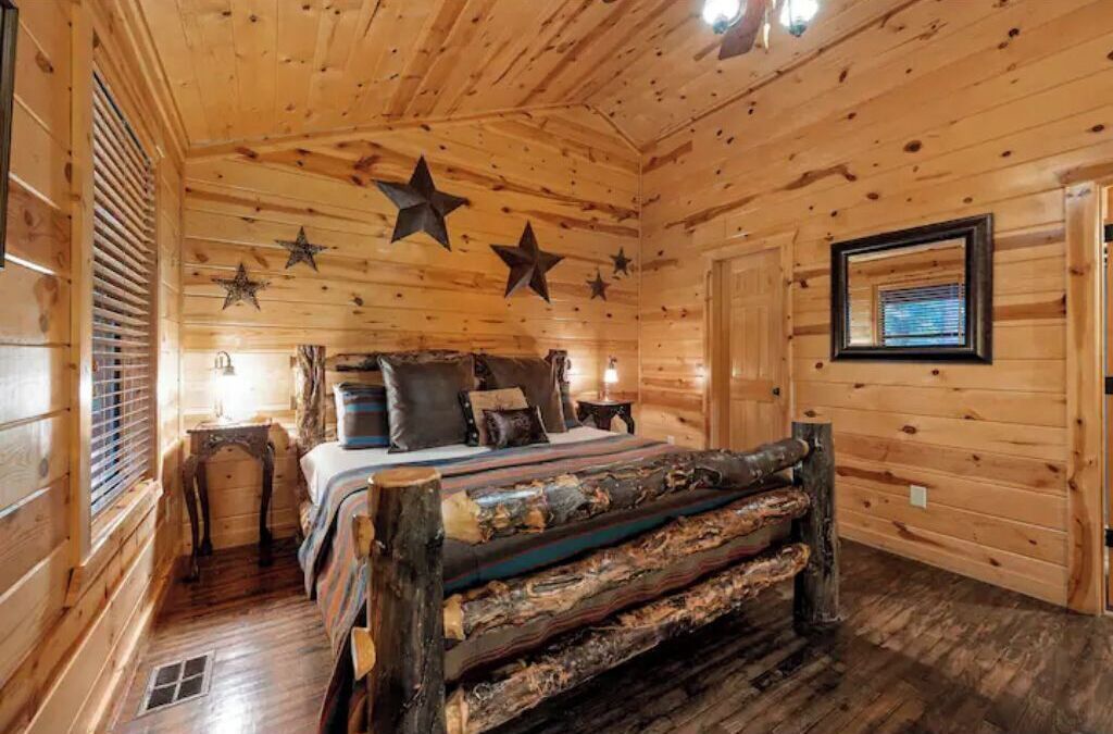 Camera da letto in una baita di legno, con un letto, cuscini, un comodino e una decorazione a stella sul soffitto.