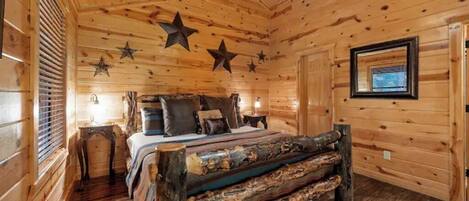 Camera da letto in una baita di legno, con un letto, cuscini, un comodino e una decorazione a stella sul soffitto.