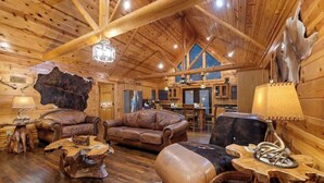 A log cabin interior with wooden floors, leather furniture, and a large fur rug. - Deer Ridge Cabin - Hochatown - Hot Tub - Firepit - Spacious Deck - Large Yard (Broken Bow)