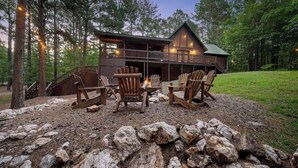 A cabin with a deck, surrounded by rocks and trees. - Deer Ridge Cabin - Hochatown - Hot Tub - Firepit - Spacious Deck - Large Yard (Broken Bow)