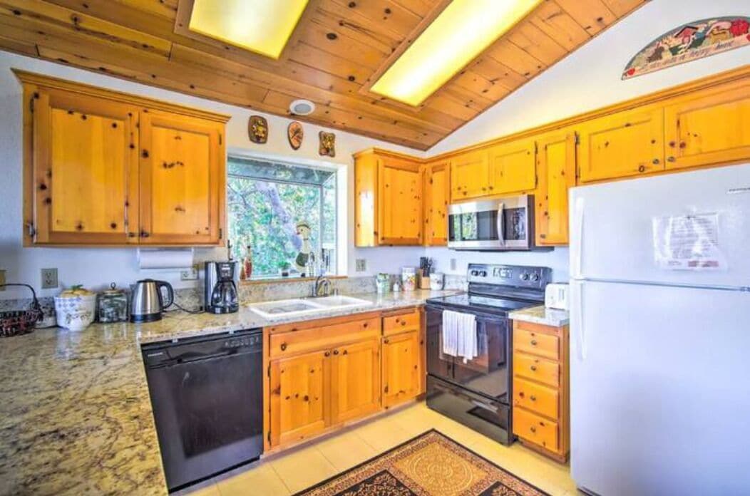 Una cocina con gabinetes de madera, un microondas, una estufa y un lavavajillas.