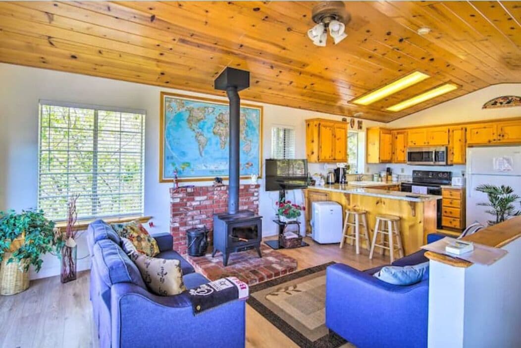 Een gezellige woonkamer met een open haard, blauwe banken en een grote wereldkaart aan de muur.