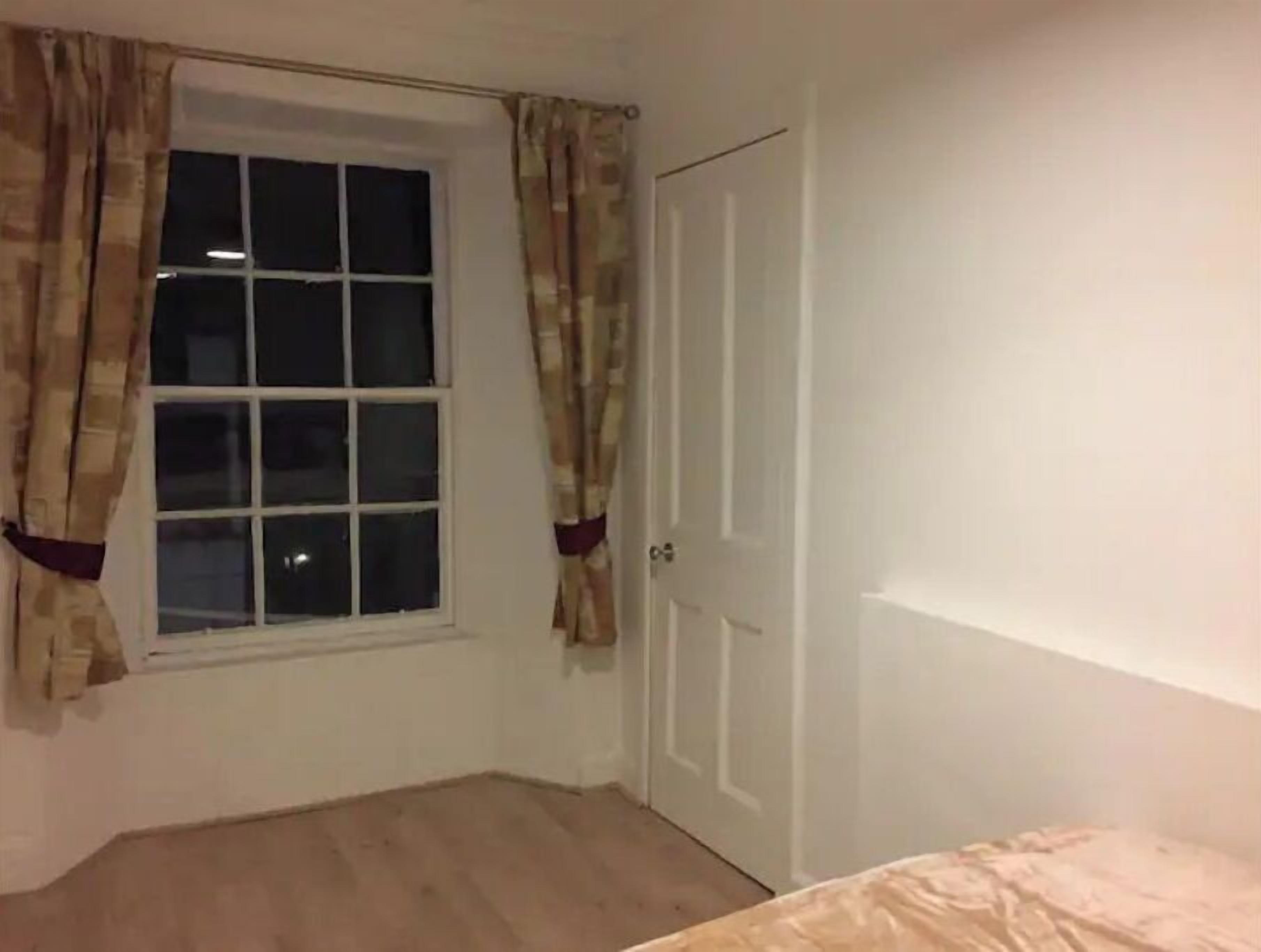 A room with a window, a door, and a bed.