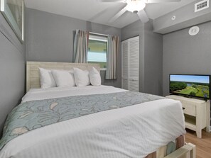 Une chambre à coucher avec un lit, une télévision et une fenêtre avec des rideaux.