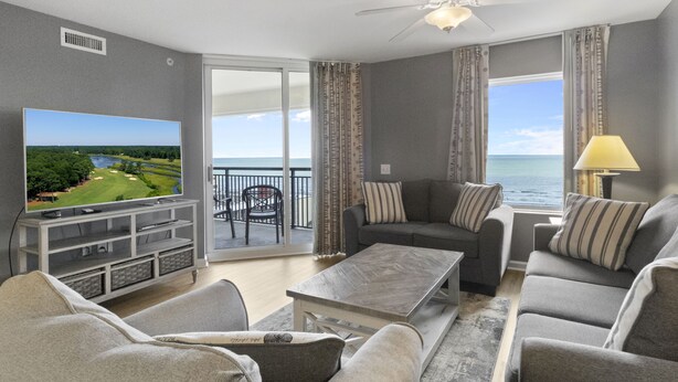 A living room with a television, sofas, a coffee table, and a balcony with a view of the ocean. - 11TH FLOOR OCEAN VIEW 3 BEDROOM WITH RESORT ACCESS | UNIT 1107 (North Myrtle Beach)