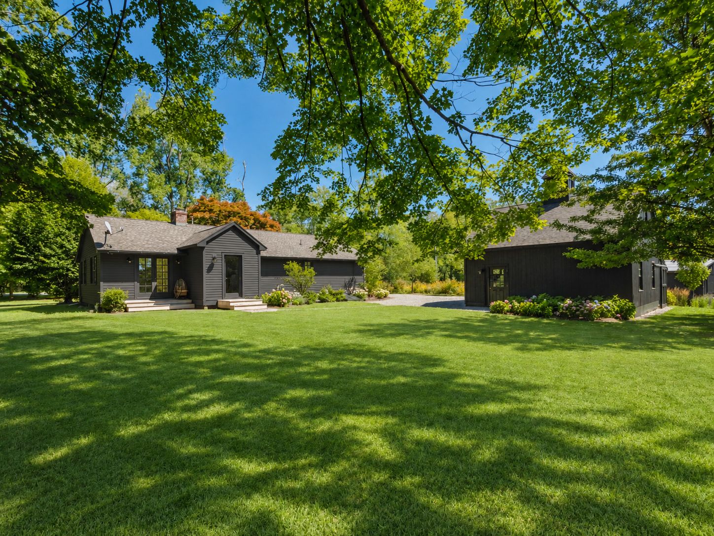 A residential property with a well-maintained lawn, a small house with a front porch, and a garage.