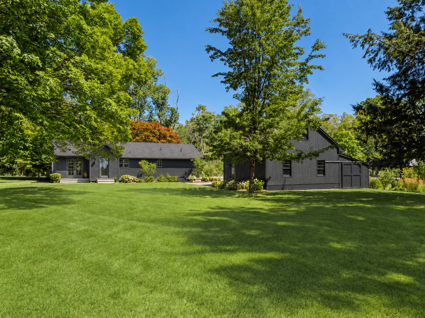 Une maison à deux étages avec une pelouse bien entretenue et de grands arbres.