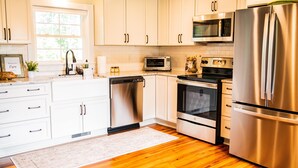 A modern kitchen with white cabinets, stainless steel appliances, and a wooden floor. - JULY DISCOUNT! Romantic 2 BR 2 story w/mountain views and stunning outdoor space (Amherst)