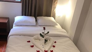A hotel room with a neatly made bed, a single rose, and a heart-shaped pillow. - Waynama Hostal (Machu Picchu)