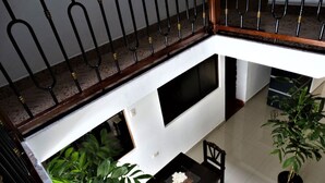 A multi-level interior with a staircase, a black-framed window, and a small table with a plant. - Waynama Hostal (Machu Picchu)