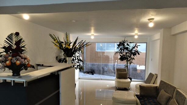 A modern living room with a glass partition, a sofa, and a coffee table. - Waynama Hostal (Machu Picchu)