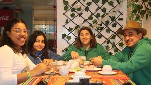 A group of people sitting at a table with a colorful tablecloth, engaged in conversation and enjoying a meal. - Waynama Hostal (Machu Picchu)