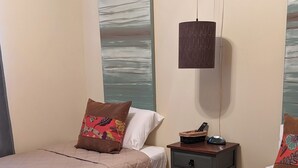 A hotel room with two beds, each with a quilted bedspread and pillows, a bedside table with a lamp, and a wall with a textured painting. - 2 BR condo-pool, remote work, golf courses, and family attractions nearby (Myrtle Beach)