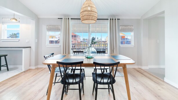Uma sala de jantar com uma mesa grande, cadeiras pretas e um lustre.