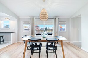 En matplats med ett stort bord, svarta stolar och en hängande lampa.