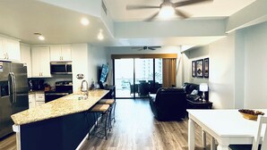 A modern kitchen with a central island, built-in appliances, and a dining area with a white table and chairs.