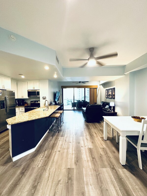 A modern kitchen with a central island, built-in appliances, and a dining area with a white table and chairs.
