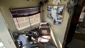 A compact room with a wooden desk, a chair, a fish decoration, a fan, and a wall-mounted light fixture. - Get off the grid in south La (Bayou Vista)