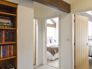 A bedroom with a bed, a wooden bookshelf, and a door leading to another room. - Apple Tree Barn- UK40791 (Minshull Vernon, near Nantwich)