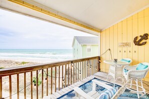 A wooden deck with a view of the beach, a small house, and a table with chairs. - Saltwater Haven - Beach Front, Ocean View (Surf City)