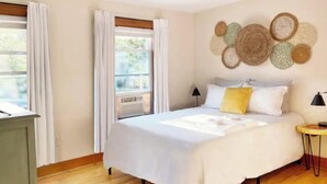 A bedroom with a bed, two bedside lamps, a bedside table, and a wall decoration.