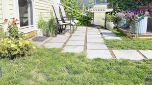 A patio with stone tiles, a grill, and outdoor seating.