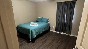 Un dormitorio con cama, ventilador de techo y ventana con cortinas.
