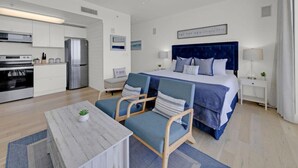 Una habitación de hotel moderna con una cama, un escritorio, una silla, una mesita y un rincón americano.