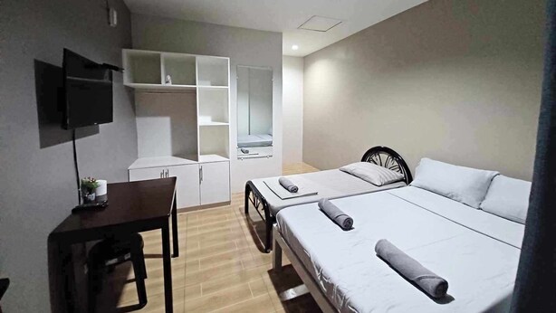 A hotel room with a bed, a desk, a chair, a TV, and a wardrobe. - 2020 Travelers Inn (Dumaguete)