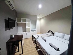 Habitación de hotel con una cama, un escritorio, una silla, un televisor y un armario.