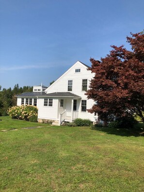 A white two-story house with a front porch and a large yard. - Charming 1870 cape cottage in Litchfield (Litchfield)