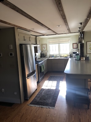 A modern kitchen with wooden beams, stainless steel appliances, and a large island. - Charming 1870 cape cottage in Litchfield (Litchfield)