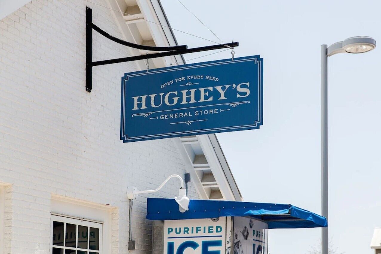 A blue sign for 'Hughey's General Store' with a black hanging bracket.