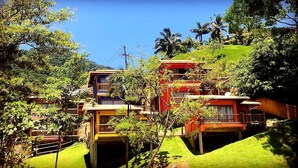 A multi-story building with balconies, surrounded by lush greenery and palm trees. - Siriúba Reserve (Ilhabela)