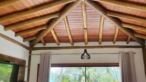 A room with a wooden ceiling, a hanging light fixture, and a window with curtains. - Siriúba Reserve (Ilhabela)