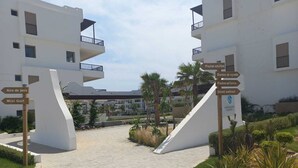 A pathway leading to a building with multiple signs indicating amenities such as a mini golf area, a pool for adults, and a street workout. - Quiet spot in Cabo negro (Cabo Negro)