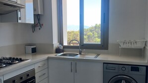 A modern kitchen with white cabinets, a gas stove, a built-in oven, a sink, and a front-loading washing machine. - Quiet spot in Cabo negro (Cabo Negro)