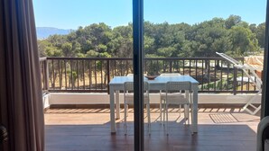 A balcony with a table and chairs, a view of trees and hills, and a clear sky. - Quiet spot in Cabo negro (Cabo Negro)