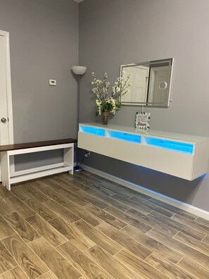 Ein Badezimmer mit weißem Waschtisch, einem Spiegel und einer Vase mit weißen Blumen.