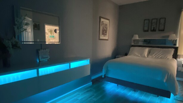 Een slaapkamer met een bed, nachtkastjes, een spiegel en een aan de muur hangend schilderij.