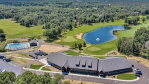 Vista aérea de um campo de golfe com um lago, um clube e uma piscina.